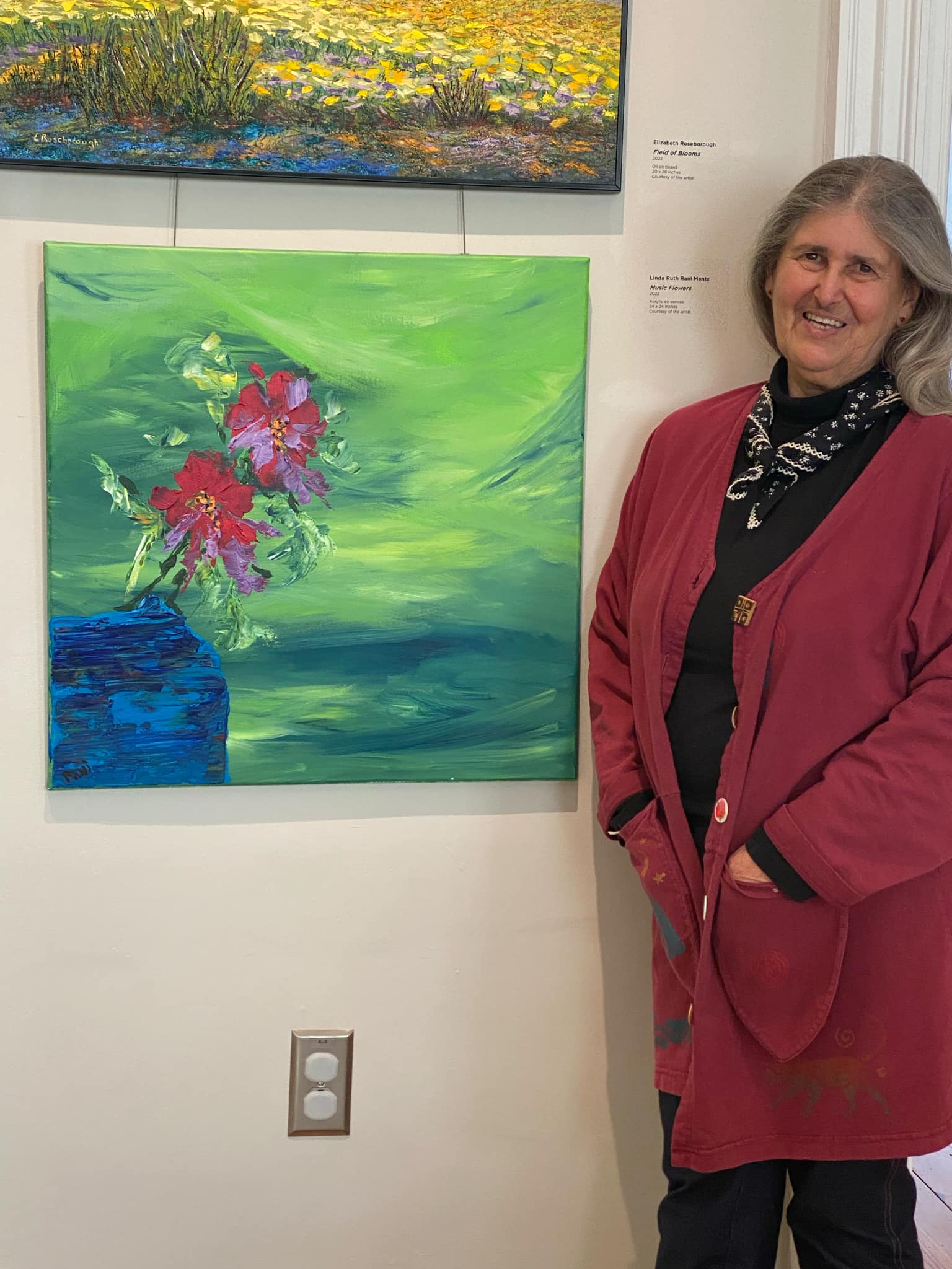 Two people browsing and discussing handmade journals and collage art at an outdoor market under a canopy